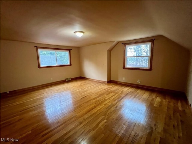 additional living space with plenty of natural light, visible vents, and wood finished floors