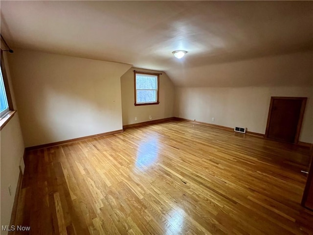 additional living space featuring lofted ceiling, visible vents, baseboards, and wood finished floors