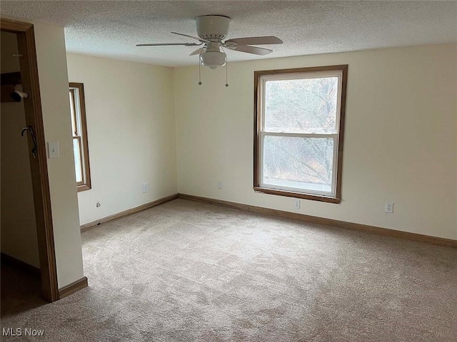 unfurnished room with a ceiling fan, carpet, a textured ceiling, and baseboards