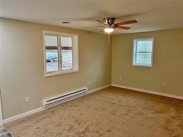 carpeted empty room with a baseboard heating unit, visible vents, ceiling fan, and baseboards