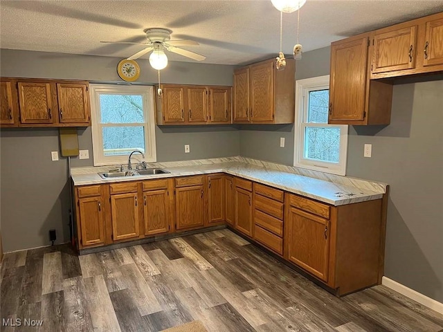 kitchen with brown cabinetry, light countertops, and a sink