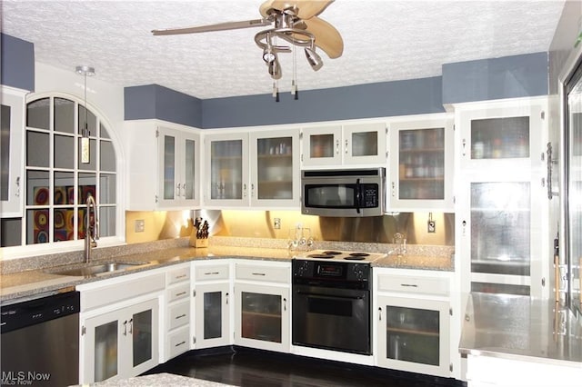 kitchen featuring appliances with stainless steel finishes, white cabinets, a sink, a textured ceiling, and light stone countertops