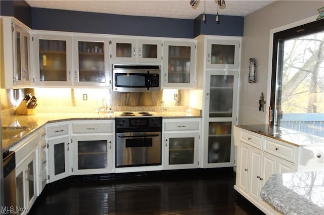 kitchen featuring light stone counters, stainless steel appliances, dark wood-type flooring, white cabinetry, and glass insert cabinets