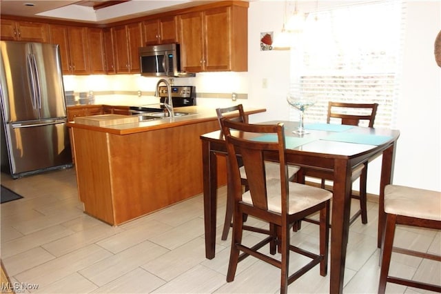 kitchen with stainless steel appliances, a peninsula, and brown cabinets