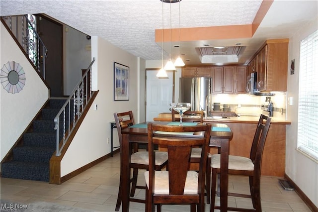 dining room featuring a textured ceiling, a tray ceiling, stairway, and baseboards