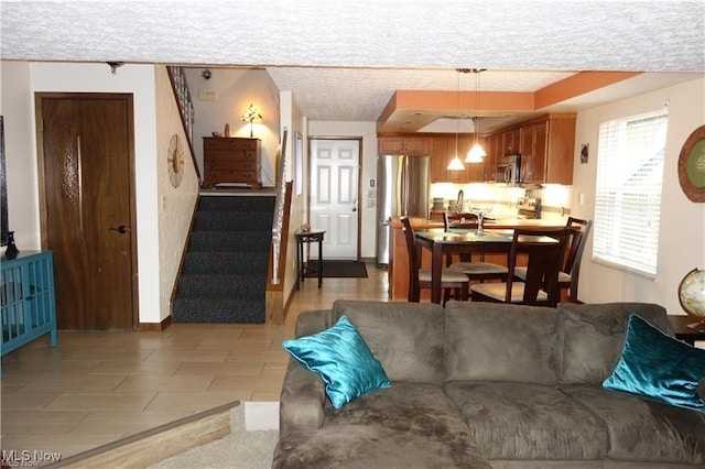 living area featuring stairs, a textured ceiling, and baseboards