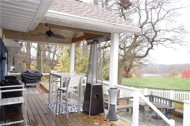 wooden terrace featuring outdoor dining area, a grill, and a ceiling fan