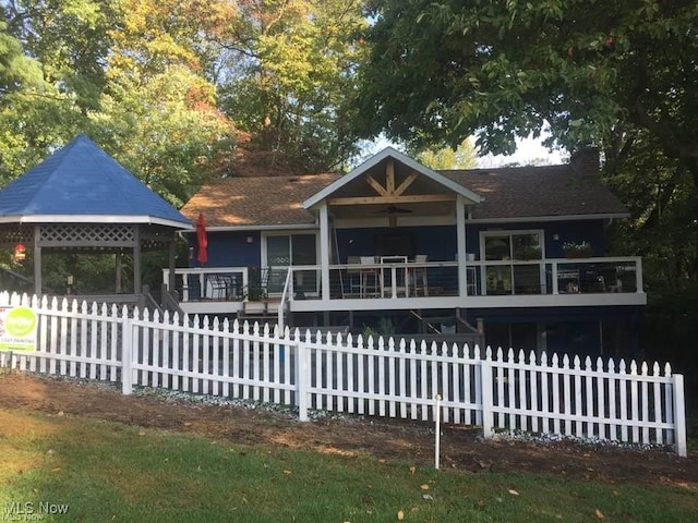 view of front of property featuring a deck, a fenced front yard, and a chimney