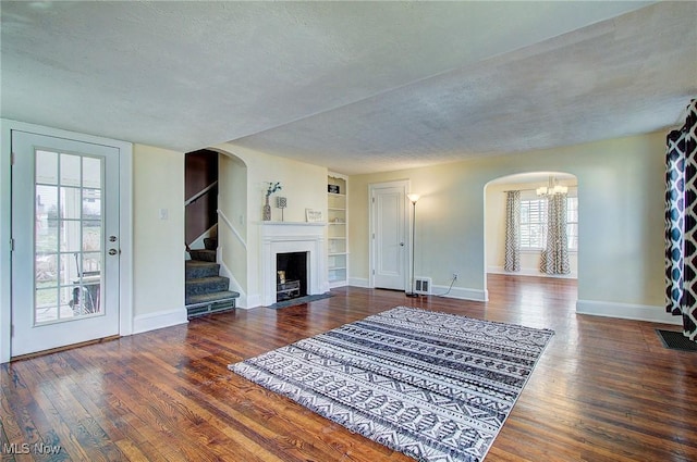 living room featuring arched walkways, a textured ceiling, and wood finished floors