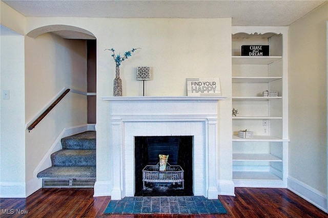 details featuring a fireplace with flush hearth, a textured ceiling, wood finished floors, and baseboards