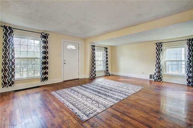 entrance foyer with a textured ceiling, visible vents, hardwood / wood-style flooring, and baseboards