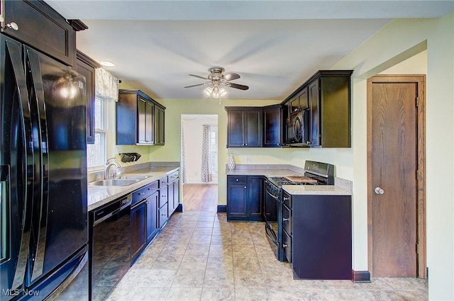 kitchen with light countertops, a sink, black appliances, ceiling fan, and baseboards