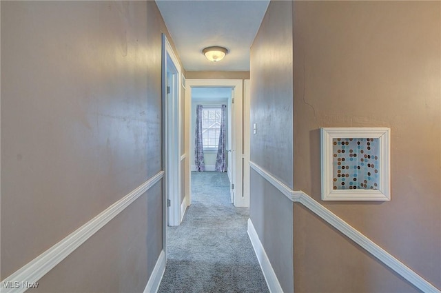 hall with carpet flooring, an upstairs landing, and baseboards