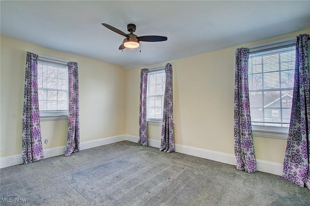 carpeted empty room with ceiling fan and baseboards