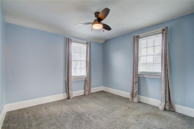 carpeted empty room with ceiling fan, a wealth of natural light, and baseboards