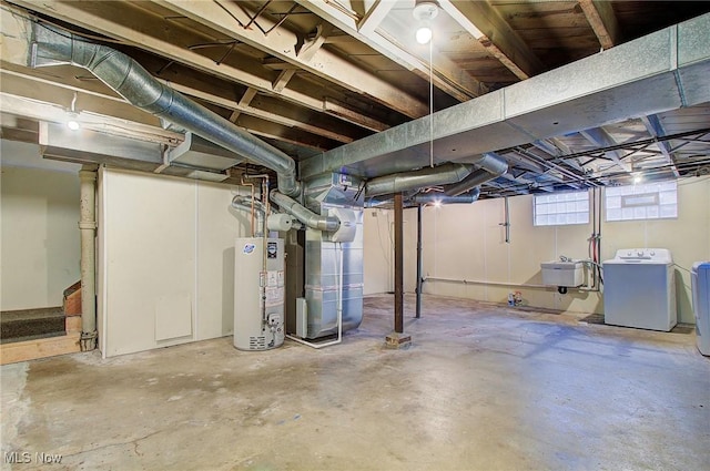 basement with washing machine and dryer, gas water heater, a sink, and heating unit