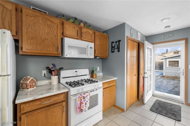 kitchen featuring brown cabinets, white appliances, light countertops, and light tile patterned floors