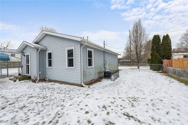 snow covered property featuring central AC and a fenced backyard