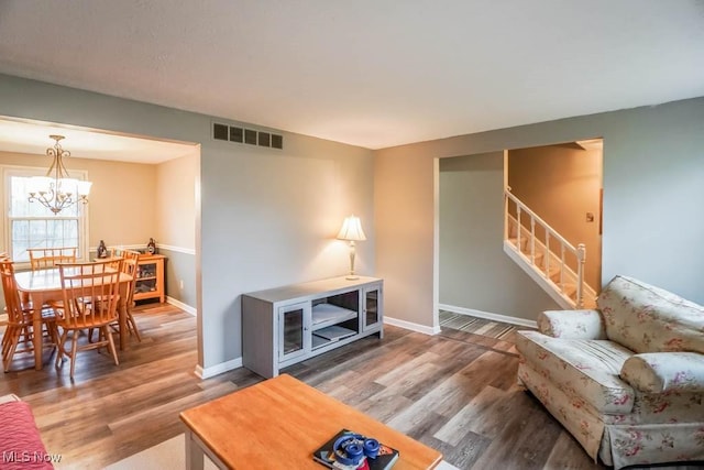 living area featuring stairway, wood finished floors, visible vents, and baseboards