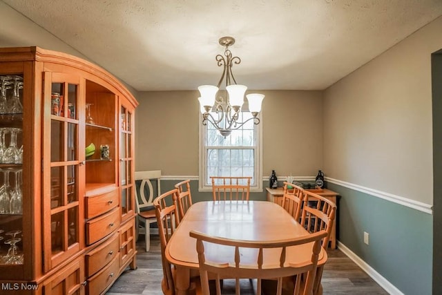 dining room featuring baseboards, dark wood-style flooring, and a notable chandelier