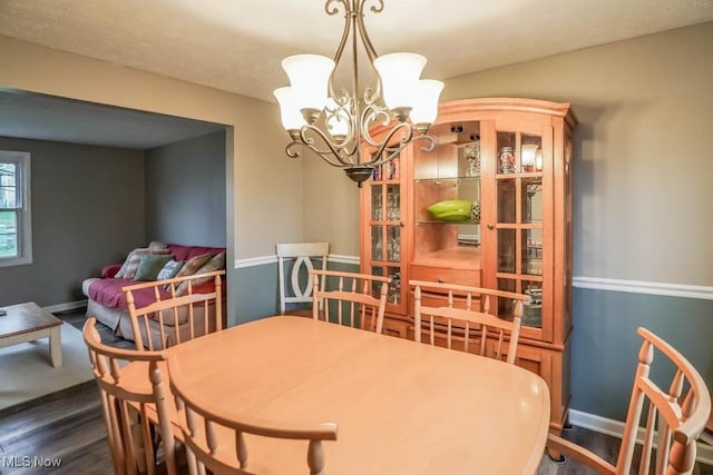 dining area featuring a chandelier, dark wood-type flooring, and baseboards