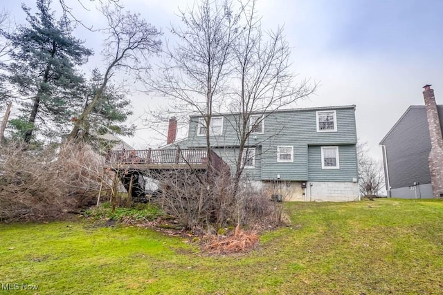 back of property with a lawn and a wooden deck