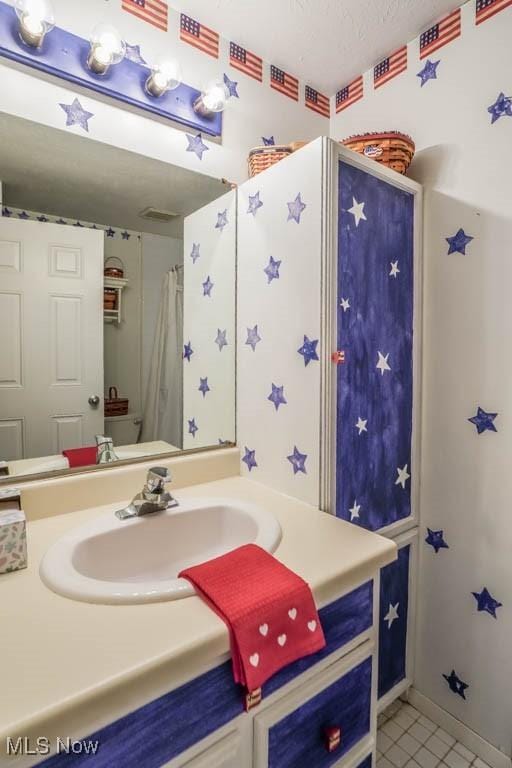 bathroom with baseboards, a textured ceiling, vanity, and tile patterned floors