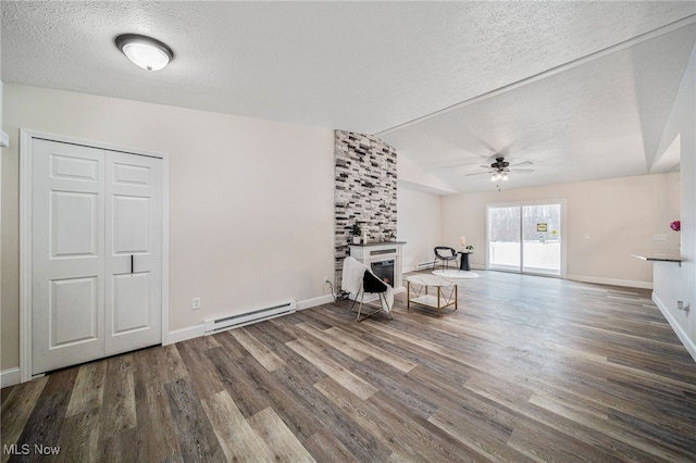 unfurnished living room with baseboard heating, a large fireplace, vaulted ceiling, a textured ceiling, and wood finished floors