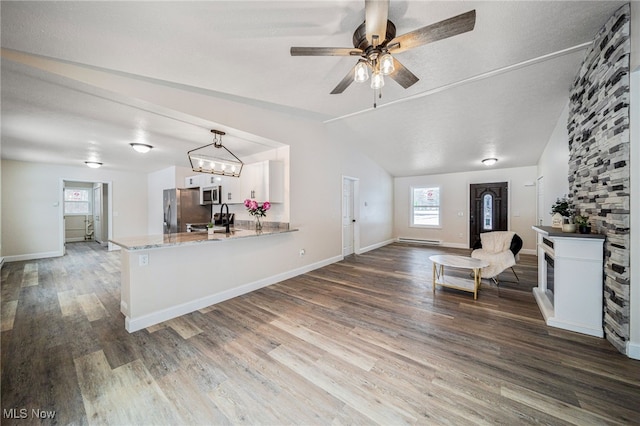 interior space with lofted ceiling, ceiling fan, baseboards, and wood finished floors