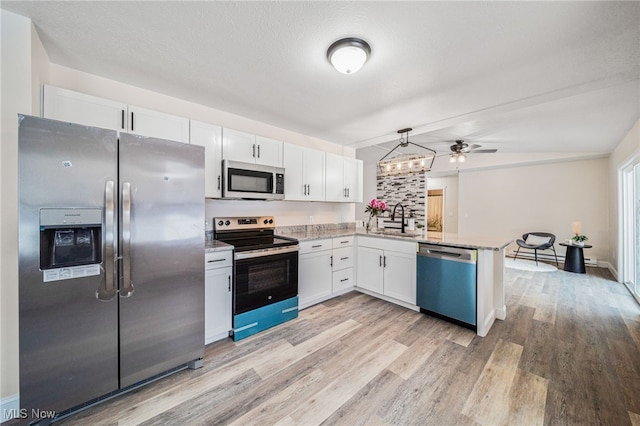 kitchen with a peninsula, white cabinetry, appliances with stainless steel finishes, and a sink