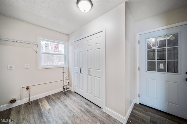 laundry room featuring laundry area, a textured ceiling, baseboards, and wood finished floors