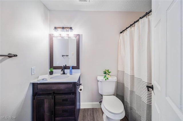 bathroom featuring toilet, a textured ceiling, vanity, wood finished floors, and baseboards