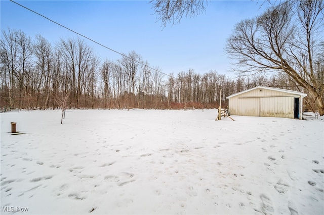 yard layered in snow featuring an outbuilding and a detached garage