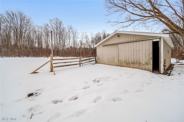 yard layered in snow with a garage, a pole building, fence, and an outdoor structure