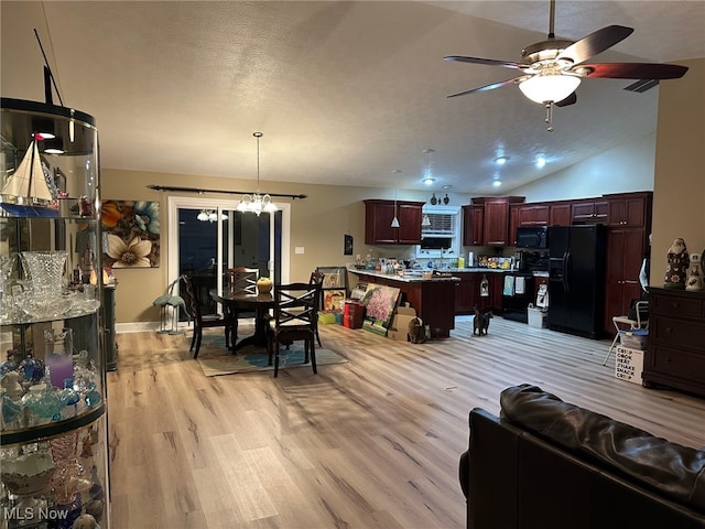 dining area with lofted ceiling, light wood-style flooring, a textured ceiling, and ceiling fan with notable chandelier