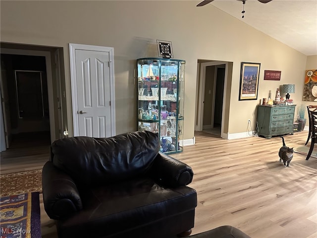 living area featuring vaulted ceiling, ceiling fan, light wood finished floors, and baseboards