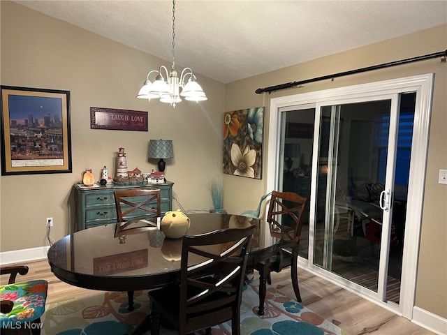 dining room with lofted ceiling, an inviting chandelier, baseboards, and wood finished floors