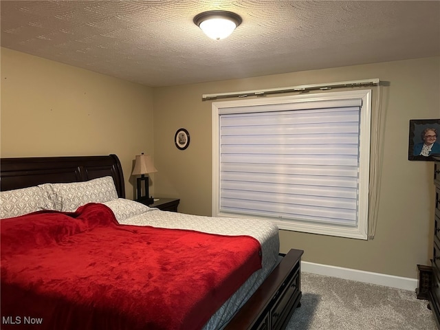 carpeted bedroom featuring a textured ceiling and baseboards