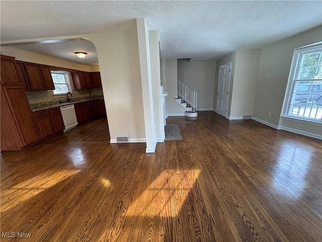 unfurnished living room featuring stairway, baseboards, visible vents, and dark wood-style flooring