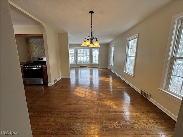 unfurnished dining area with dark wood-style floors, baseboards, visible vents, and a chandelier