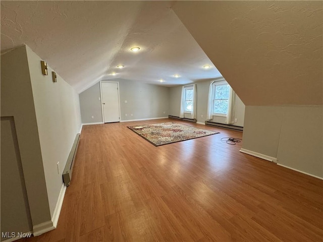 bonus room featuring a baseboard radiator, a textured ceiling, and wood finished floors