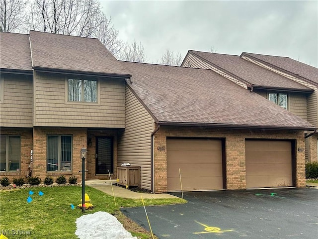 multi unit property featuring a shingled roof, brick siding, an attached garage, and aphalt driveway