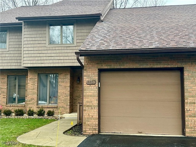 view of front of home featuring a shingled roof, brick siding, and a garage