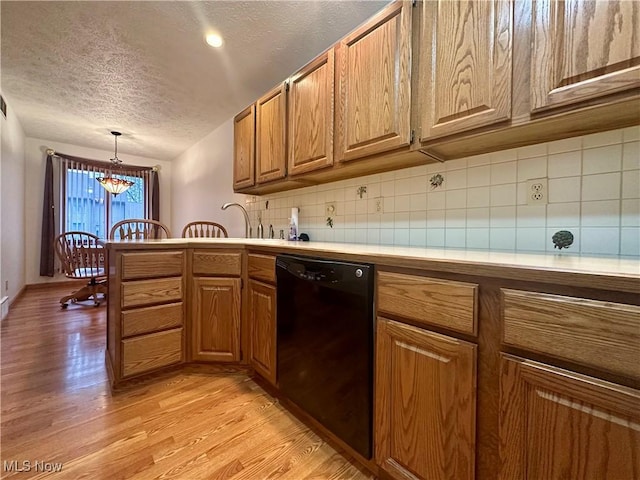 kitchen featuring light wood finished floors, light countertops, backsplash, an inviting chandelier, and dishwasher