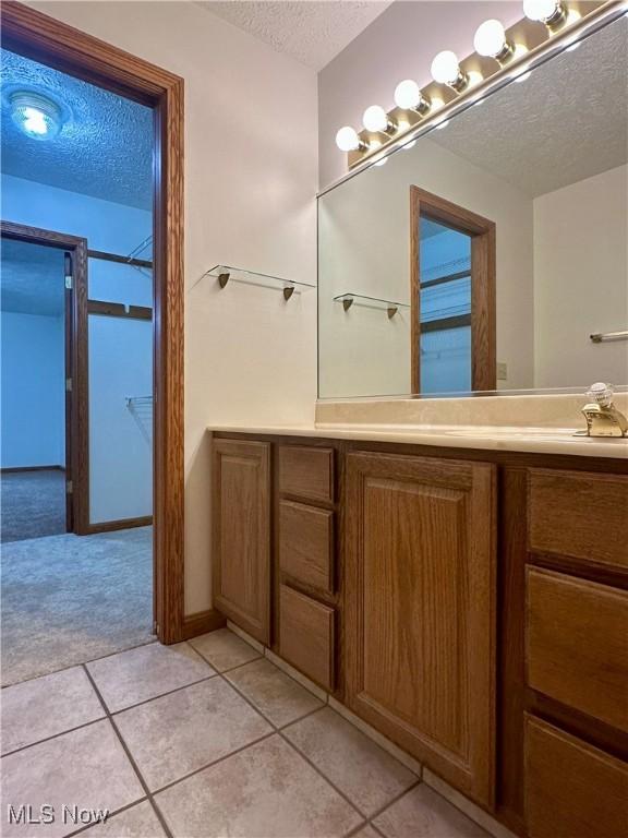 bathroom with tile patterned flooring, a textured ceiling, and vanity