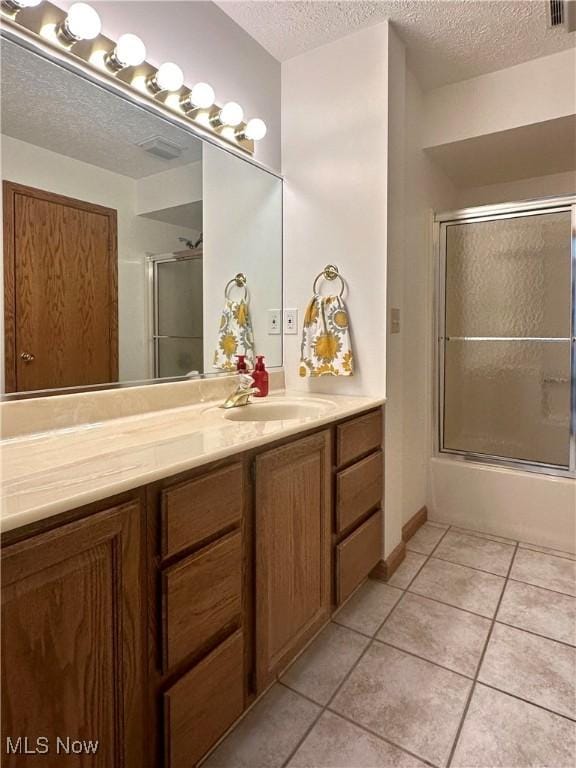 bathroom with shower / bath combination with glass door, a textured ceiling, vanity, and tile patterned floors