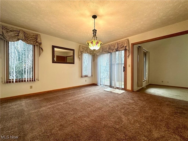 carpeted spare room with a textured ceiling and baseboards