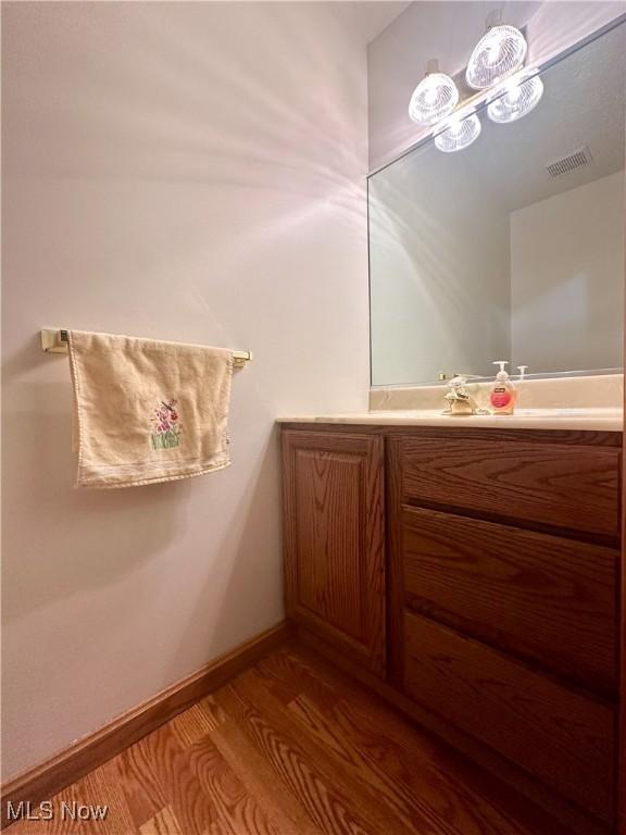 bathroom featuring vanity, wood finished floors, visible vents, and baseboards