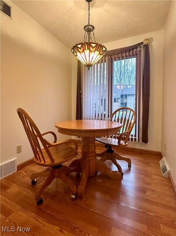 dining room featuring wood finished floors, visible vents, and baseboards