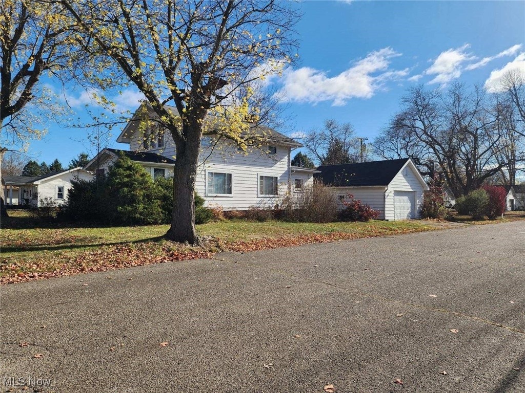 view of front of property featuring a garage, a front lawn, and an outdoor structure